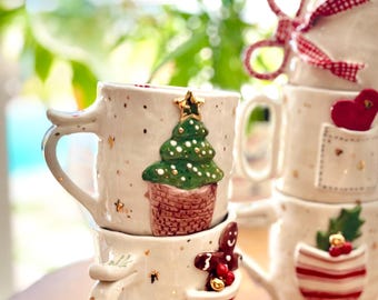 May include: A set of four white ceramic mugs with festive Christmas designs. The mugs feature a gingerbread man, a Christmas tree, a red and white striped stocking, and a red heart with a pocket. Each mug has a gold speckled glaze and a white handle.