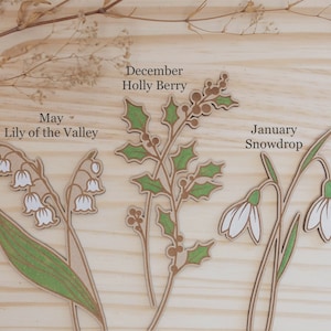 White birth month flowers are May lily of the Valley and January snowdrop. December is green leaves with engraved holly berries