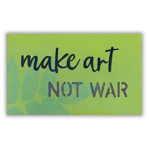May include: A green wooden sign with the text "make art not war" in black lettering. The sign has a light green leaf design in the background.