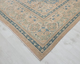 May include: A vintage rug with a beige background and a blue and green floral pattern. The rug has a border with a repeating pattern of blue and green.