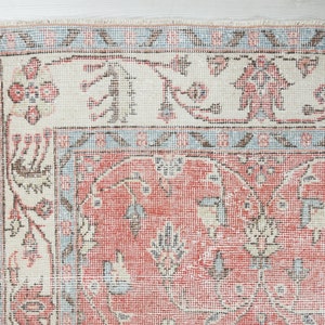 May include: Close-up of a vintage rug with a red, white and blue floral pattern. The rug has a distressed look and is made of a woven material.