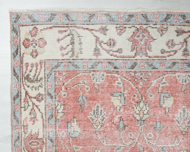 May include: Close-up of a vintage rug with a red, white and blue floral pattern. The rug has a distressed look and is made of a woven material.