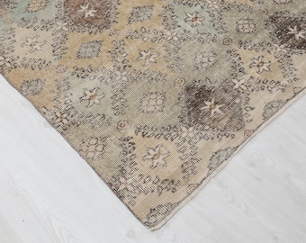 Può includere: Un tappeto vintage con uno schema di colori sbiaditi, marrone chiaro e verde. Il tappeto presenta un motivo geometrico ripetitivo con un delicato design floreale.
