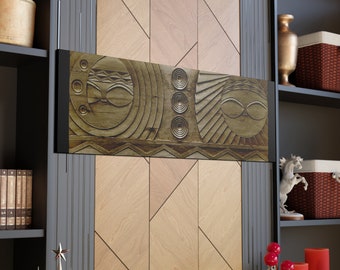 May include: A wooden wall art piece with a carved design of two faces and a circle with concentric rings. The art piece is mounted on a wall with a dark gray trim.