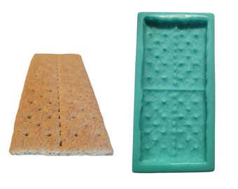 May include: A green silicone mold for making graham cracker-shaped treats. The mold is divided into two sections, each with a textured surface that resembles a graham cracker.