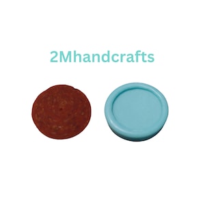 May include: A round, reddish-brown object next to a light blue, circular object. The reddish-brown object appears to be a slice of salami. The light blue object has a raised edge. The text "2Mhandcrafts" is in the image.