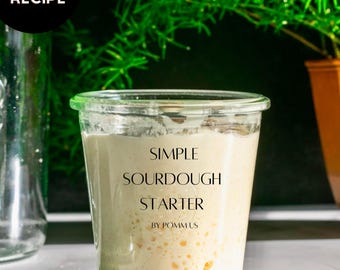 May include: A glass jar with a white lid filled with a bubbly sourdough starter. The jar is labeled "SIMPLE SOURDOUGH STARTER BY POMMUS".