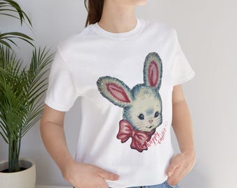May include: White t-shirt with a glittery blue and pink bunny rabbit graphic and the text "Happy Easter" printed on the front.