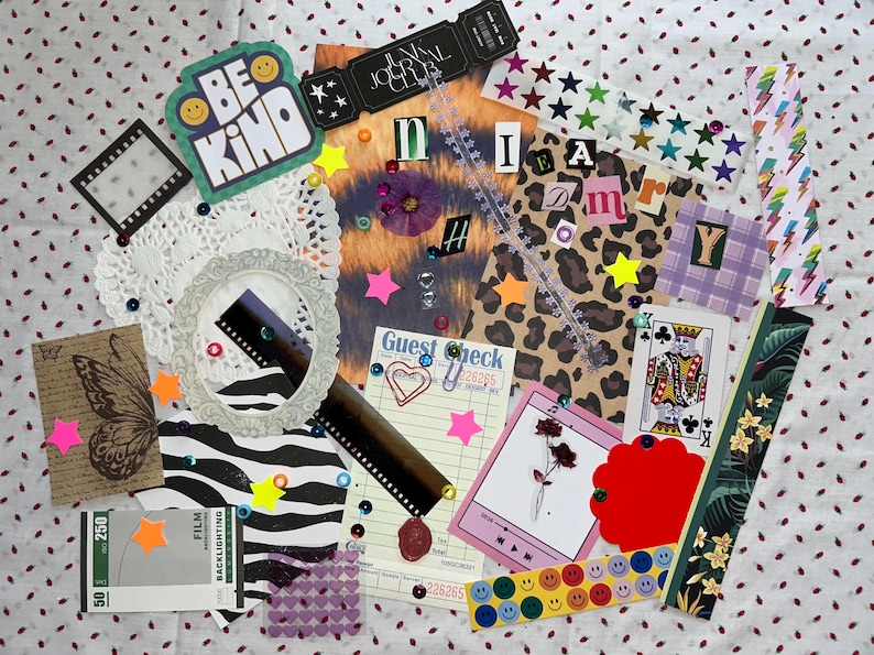 May include: A collage of decorative paper ephemera, including a doily, film strips, and a "Be Kind" sticker. Other elements include a playing card, a guest check, and various stickers and embellishments. The color palette is diverse, with pink, yellow, and green accents.