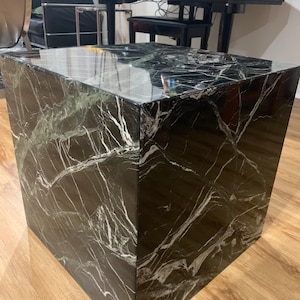 May include: A square black and green marble coffee table with a polished surface.