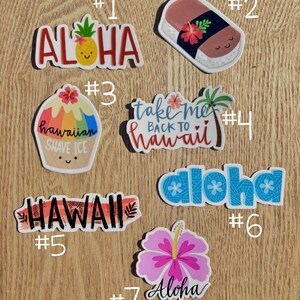 May include: Seven colorful stickers with Hawaiian themes. The stickers feature phrases like "Aloha", "Take Me Back To Hawaii", and "Hawaiian Shave Ice".