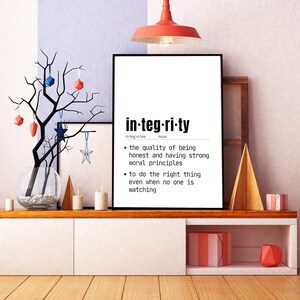 May include: A framed print with the word "integrity" in a bold, modern font. The definition of integrity is listed below the word. The print is displayed on a white cabinet with decorative items, including candles and a decorative tree.