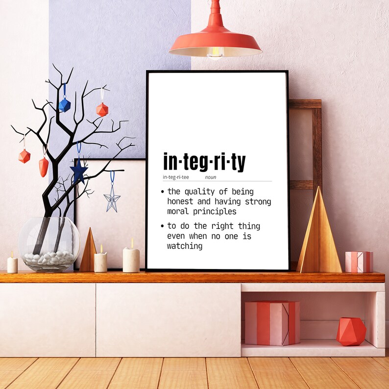 May include: A framed print with the word "integrity" in a bold, modern font. The definition of integrity is listed below the word. The print is displayed on a white cabinet with decorative items, including candles and a decorative tree.