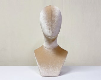 May include: A beige velvet bust form for displaying jewelry or accessories.