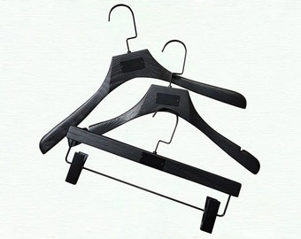 May include: Three black wooden hangers with a black metal bar. The hangers are stacked on top of each other.