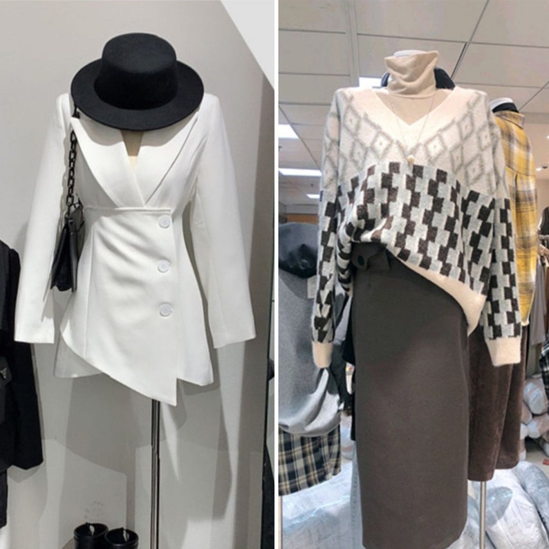 May include: Two mannequins showcase fashion ensembles. One presents a white blazer with an angled hem, complemented by a black hat and handbag. The other displays a patterned sweater over a roll-neck top and a dark brown skirt, offering a contrast in textures and colours.