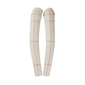 May include: Two off-white, cylindrical fabric objects with a red grid pattern. The objects are vertically oriented and appear to be made of a natural fiber material. The ends are closed, suggesting a stuffed or filled construction.