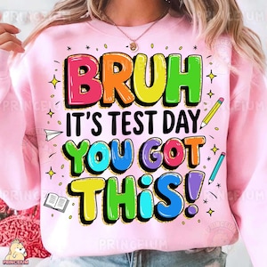 May include: Pink sweatshirt with a colourful graphic print that says "Bruh it's test day you got this!"