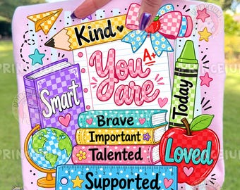 May include: A light pink fabric featuring a colorful school-themed graphic with a notebook, a globe, a pencil, a crayon, and an apple. The text reads Kind, You Are, Smart, Brave, Important, Talented, Supported, Today, and Loved, with A+ and stars.