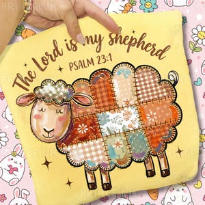 Może przedstawiać: Żółta poduszka z motywem owcy. Owca wykonana jest z patchworkowej tkaniny w odcieniach brązu, pomarańczy i błękitu. Na poduszce wydrukowano tekst "The Lord is my shepherd" i "Psalm 23:1".