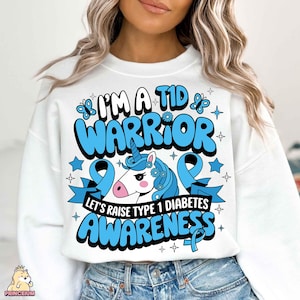 May include: White sweatshirt with a blue and white unicorn graphic and the text "I'm a T1D Warrior Let's Raise Type 1 Diabetes Awareness".