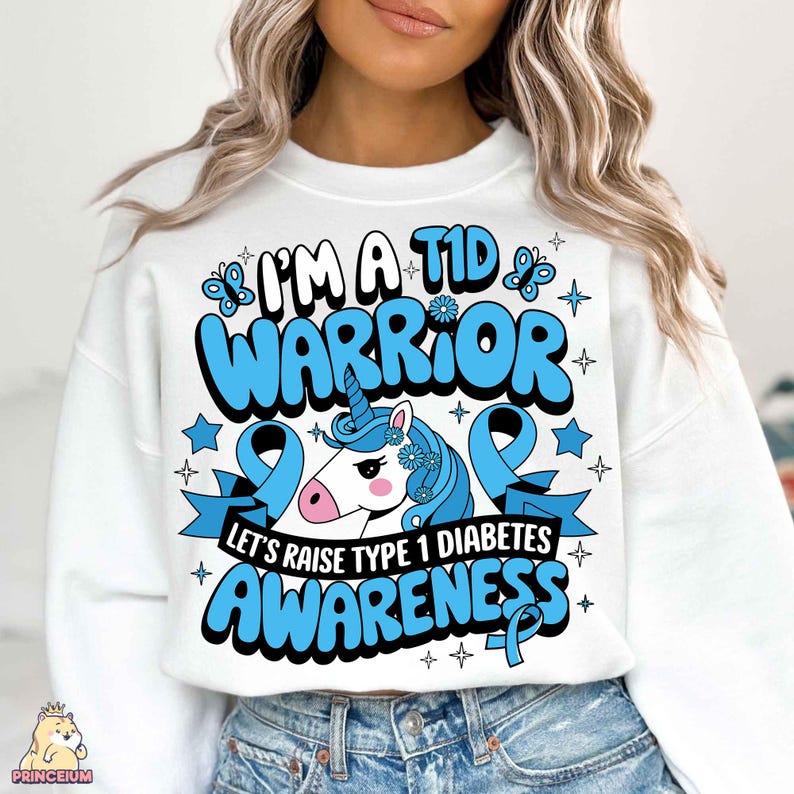 May include: White sweatshirt with a blue and white unicorn graphic and the text "I'm a T1D Warrior Let's Raise Type 1 Diabetes Awareness".