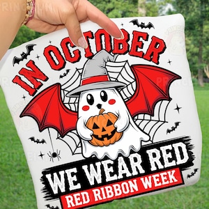 May include: White Halloween-themed pillow with a cartoon ghost wearing a witch hat and holding a pumpkin. The text "IN OCTOBER WE WEAR RED RED RIBBON WEEK" is displayed in red and black.
