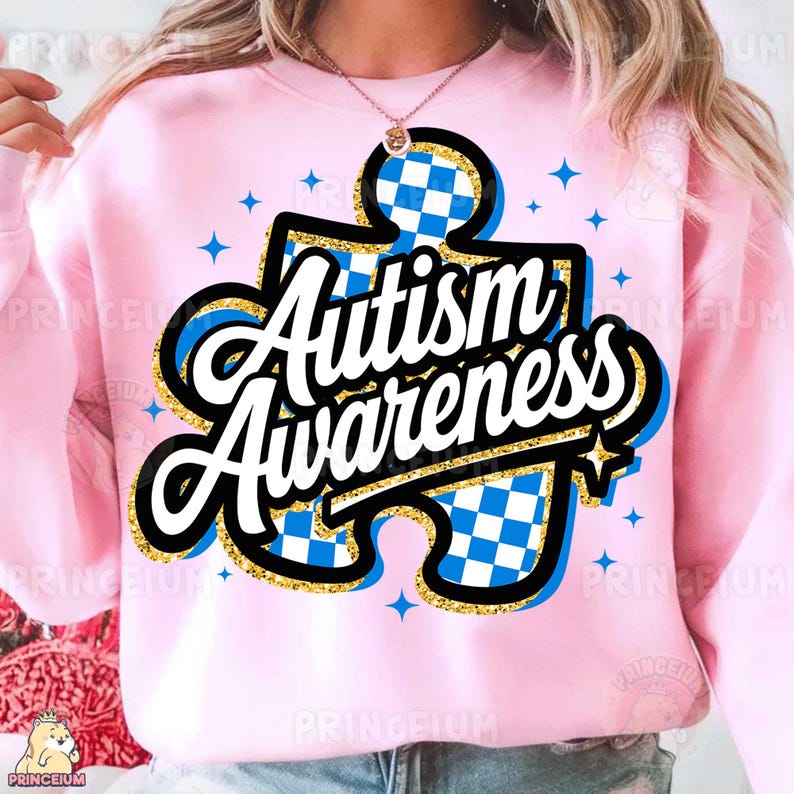 May include: Pink sweatshirt featuring a blue and white jigsaw piece design with the text "Autism Awareness" in gold glitter lettering.