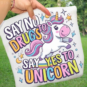 May include: White pillow with a cartoon unicorn design. The unicorn has a yellow horn, pink nose, and a colorful mane and tail. Text on the pillow reads "SAY NO TO DRUGS SAY YES TO UNICORN" in various colors and fonts.