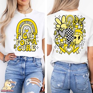 May include: White t-shirt with a yellow rainbow and the text "Fight for a Cure" on the front. The back of the shirt features a yellow ribbon, hearts, butterflies, and other designs.