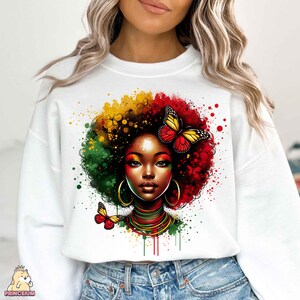 K&ouml;nnte beinhalten: Wei&szlig;er Pullover mit einem bunten Grafikdruck einer Frau mit Afrofrisur und Schmetterlingen. Die Grafik ist in Rot-, Gr&uuml;n-, Gelb- und Schwarzt&ouml;nen gehalten.