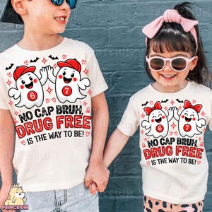 May include: Two off-white t-shirts featuring a graphic of two cartoon ghosts high-fiving. The ghosts wear red caps and have red circles with the numbers 6 and 7 on their chests. Text reads: NO CAP BRUH, DRUG FREE IS THE WAY TO BE!