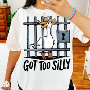 May include: White t-shirt with a cartoon illustration of a goose wearing a cowboy hat and boots, behind bars. The text "Got Too Silly" is printed below the image.