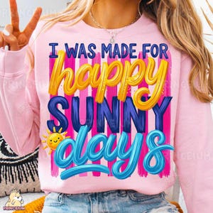 Może przedstawiać: Jasnor&oacute;żowa bluza z napisem "I WAS MADE FOR happy SUNNY days" w kolorze ż&oacute;łtym, niebieskim i białym. Projekt zawiera uśmiechnięte słońce i pionowe r&oacute;żowe i fioletowe paski.