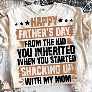 Pu&ograve; includere: Una t-shirt a maniche corte color crema con testo nero e marrone che recita: HAPPY FATHER'S DAY FROM THE KID YOU INHERITED WHEN YOU STARTED SHACKING UP WITH MY MOM. Il design include stelle nere e barre orizzontali marroni.