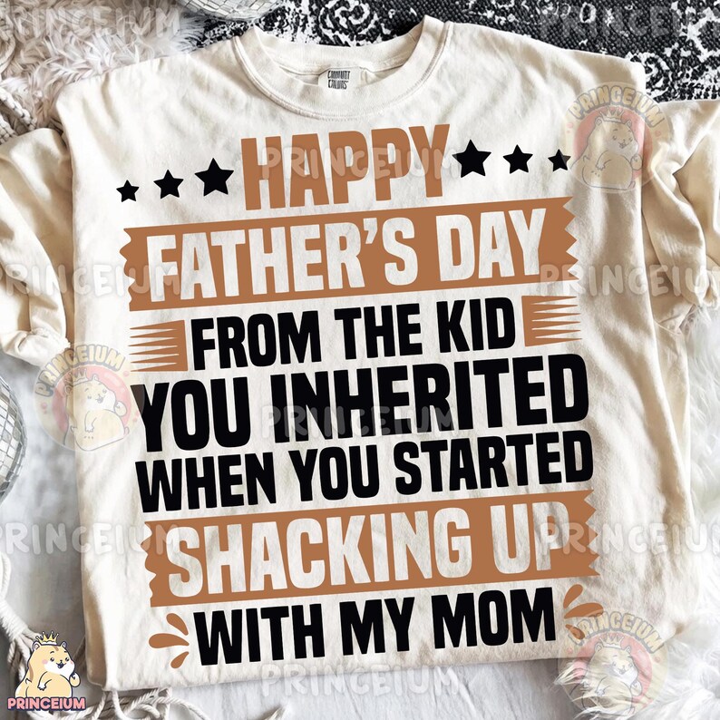 Pu&ograve; includere: Una t-shirt a maniche corte color crema con testo nero e marrone che recita: HAPPY FATHER'S DAY FROM THE KID YOU INHERITED WHEN YOU STARTED SHACKING UP WITH MY MOM. Il design include stelle nere e barre orizzontali marroni.
