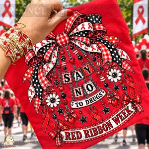 Puede incluir: Una camiseta roja con el gráfico de un lazo grande con patrones de cuadros vichy rojos y blancos, lunares negros y blancos y estampado de leopardo. El diseño incluye cadenas colgantes con cuentas, flores, corazones, estrellas y cintas rojas con el texto SAY NO TO DRUGS.