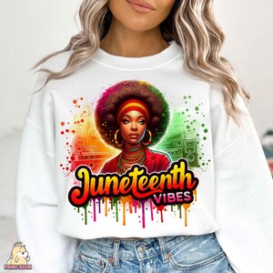 K&ouml;nnte beinhalten: Wei&szlig;es Sweatshirt mit einem bunten Grafikdesign, das eine Frau mit Afro zeigt, die eine rote Jacke und Schmuck tr&auml;gt. Die Grafik enth&auml;lt auch den Text "Juneteenth Vibes".