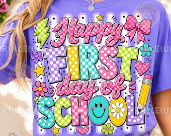 May include: A purple t-shirt featuring a colorful graphic with the text Happy FIRST day of SCHOOL. The design includes a checkered lightning bolt, a pink bow, a yellow pencil, a smiley face, and various flowers and hearts in bright colors.