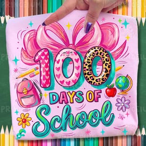 May include: A light pink t-shirt with a colourful graphic celebrating 100 days of school. The design includes a large pink bow, the number 100 with heart and leopard print details, a backpack, pencils, an apple, and a globe.