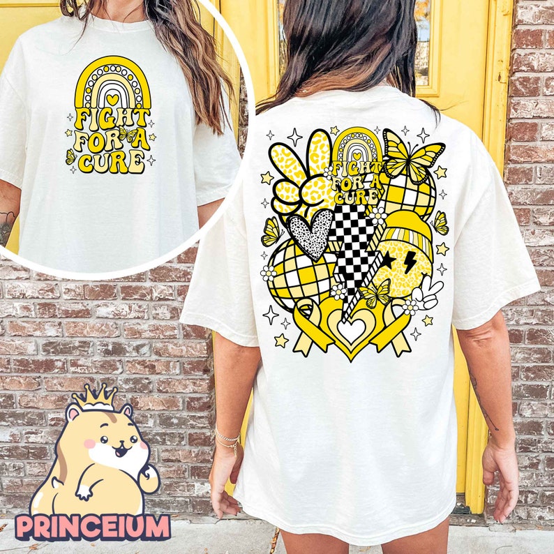 May include: White t-shirt with a yellow graphic on the back. The graphic includes a rainbow, hearts, butterflies, stars, and the text "Fight for a Cure".
