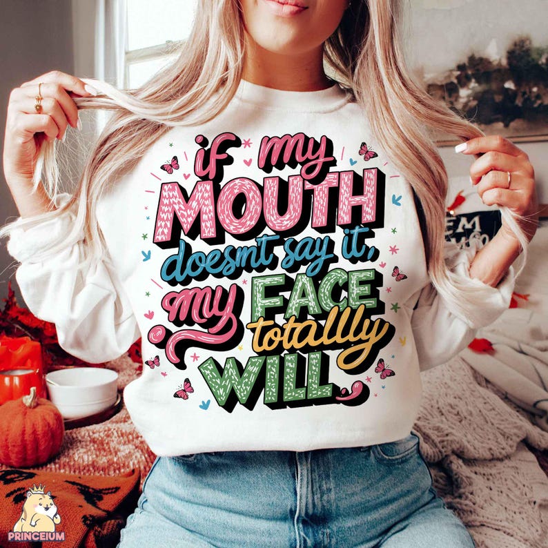 May include: White sweatshirt with a colorful graphic that says "If my mouth doesn't say it, my face totally will."