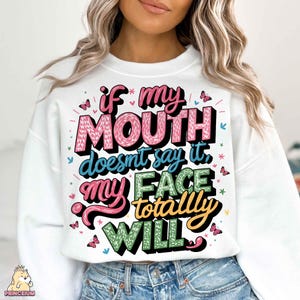 May include: White sweatshirt with a colorful graphic print that says "if my mouth doesn't say it, my face totally will".