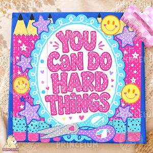 May include: A square sign with a blue background featuring pink pencils, purple stars, and yellow smiley faces. The center has a white scalloped frame with the text "YOU CAN DO HARD THINGS" in pink polka-dot letters and a pair of scissors below.