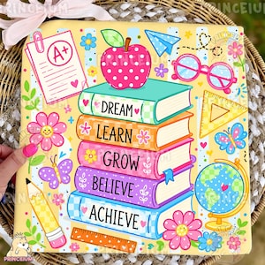 May include: A square decorative sign with a yellow background featuring a stack of five colorful books labeled Dream, Learn, Grow, Believe, and Achieve. Surrounding the books are illustrations of an apple, pencil, globe, ruler, and flowers.