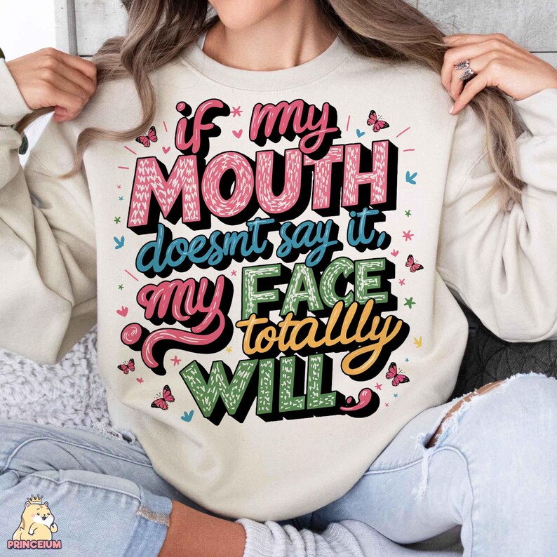 May include: A cream-colored sweatshirt with a colorful graphic print that reads "If my mouth doesn't say it, my face totally will."