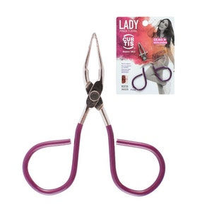 May include: Purple handled eyebrow tweezers with a silver metal body. The tweezers are designed to grip and pluck hairs. The packaging shows a woman with styled eyebrows and the text "Lady Pinza Tijera Curtis Modelo 58LC".