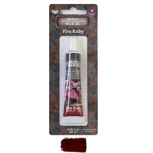 May include: A tube of Fire Ruby antique brilliance wax, 0.68 fl. oz. (20 ml), on a brown and rust-colored card. The tube is black with white text and a red label. A swatch of the wax is shown at the bottom.