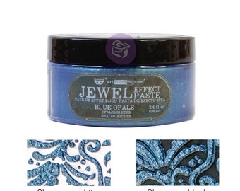 Puede incluir: Un tarro de pasta de efecto joya de ópalo azul, etiquetado como "Jewel Effect Paste" y "Blue Opals". El tarro es de 3,4 fl. oz (100 ml). La pasta se muestra aplicada sobre una superficie blanca y una superficie negra.
