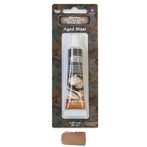 May include: A tube of Art Alchemy Metallique Wax in Aged Brass. The tube is in a clear plastic package with the product name and details printed on it. The wax is a metallic bronze color, and the package includes a color swatch.
